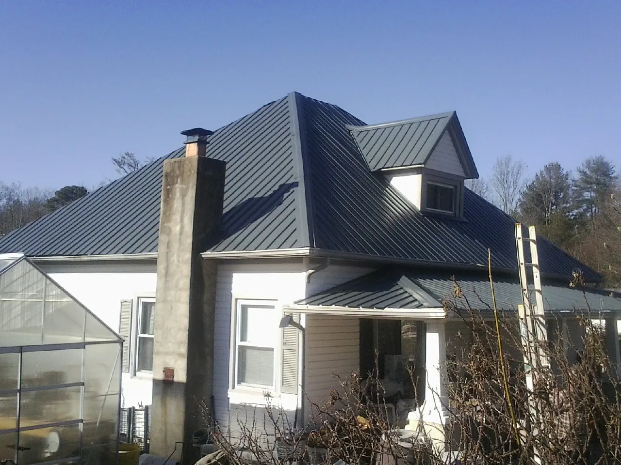 Dark blue standing seam metal roof on a white farmhouse with dormer — Slate & Tile Roof Repair by Roofing Brothers in Cotuit