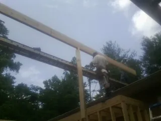Carpenter setting a ridge beam over a new addition frame — Ice Dam Removal by Roofing Brothers in Cotuit