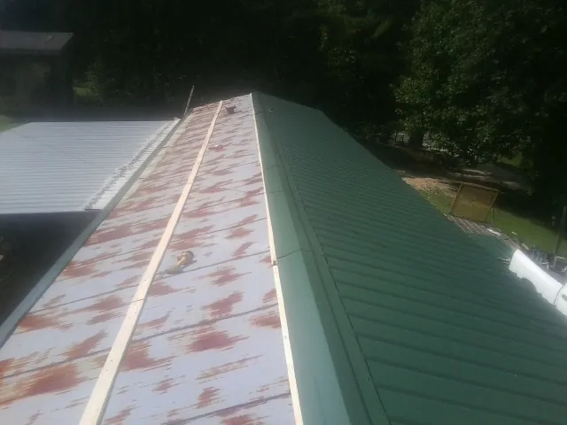 Old rusted panels beside newly installed green metal roofing — Wind Damage Roof Repair by Roofing Brothers in Cotuit