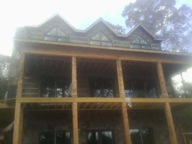 Dormers and porch framing on a large log home under construction — Roof Coating work by our crew in Cotuit