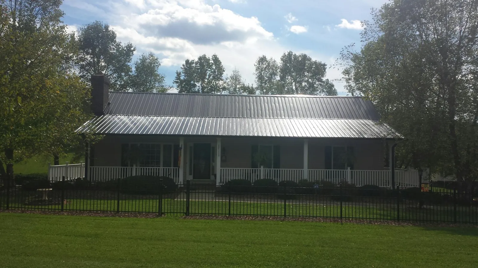 Gray metal roof on a brick ranch with a full width front porch — Gutter Guard Installation work by our crew in Cotuit